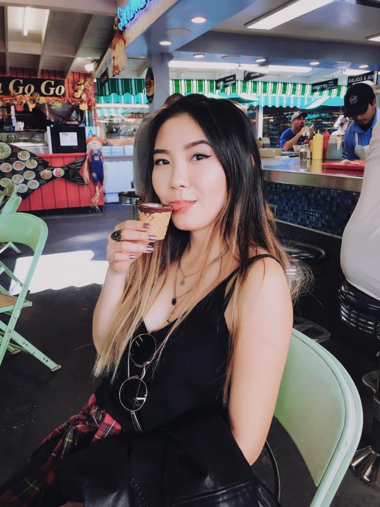 girl sitting with coffee in waffle cone cup in los angeles california outdoor food market