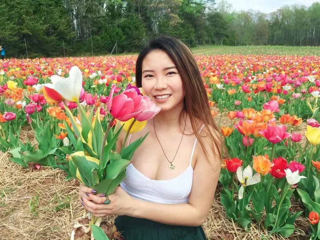 asian girl standing in a field of tulips holding tulips
