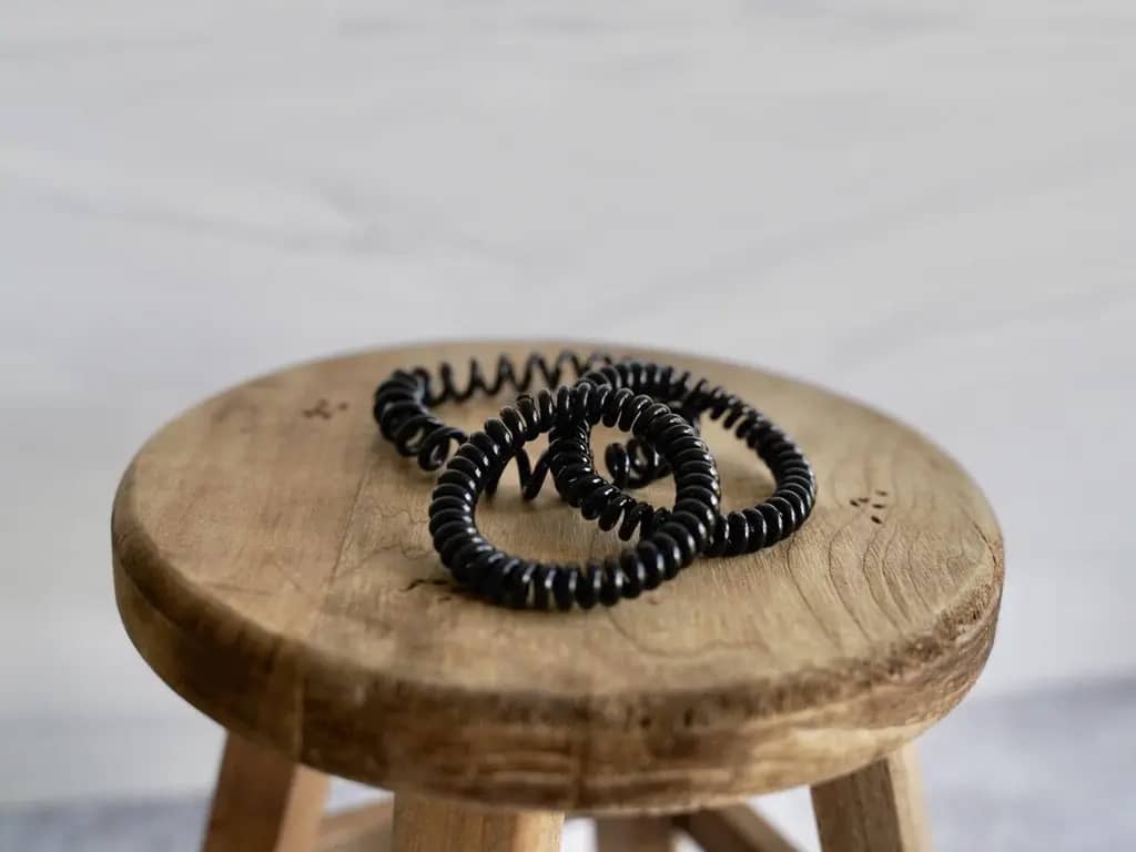 3 black invisibobble hair ties bands on wood stool