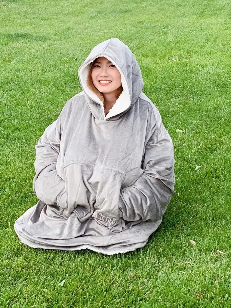 girl in a grey the comfy sweater blanket sitting on green grass