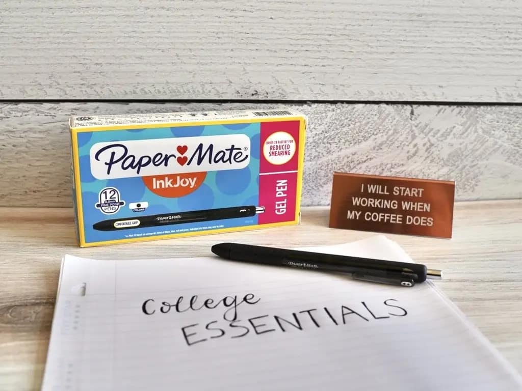 box of black paper mate gels pens with lined paper with college essentials written on it and a rosegold sign
