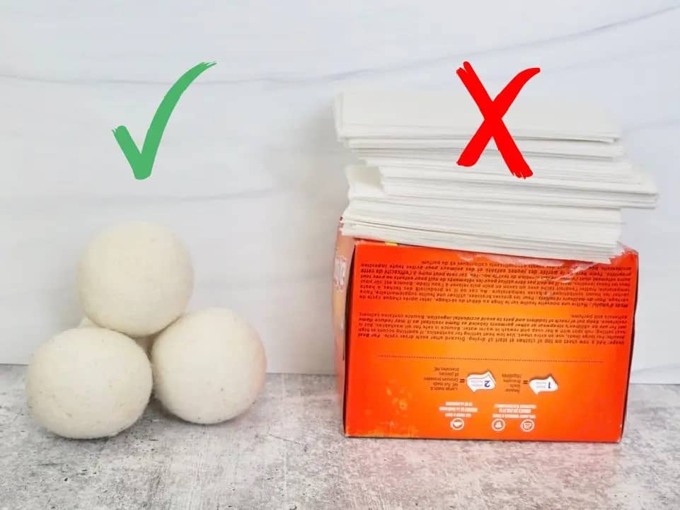 three wool dryer balls next to orange box with stack of dryer sheets