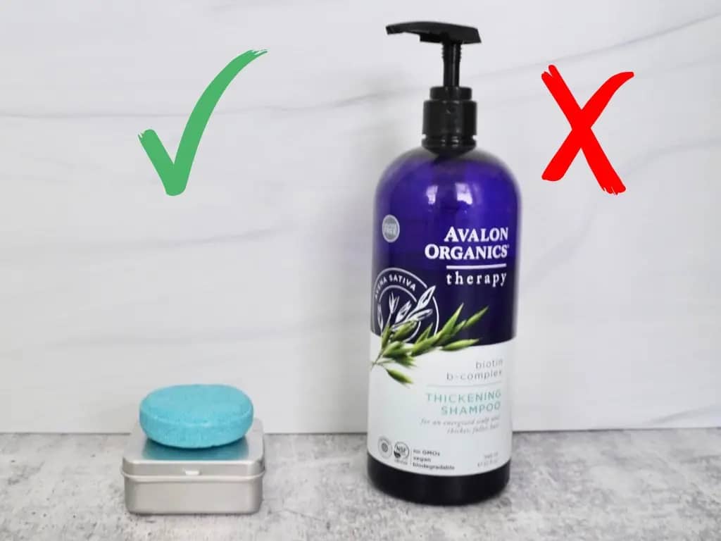 blue shampoo bar on top of metal tin container next to a big plastic violet organic shampoo bottle